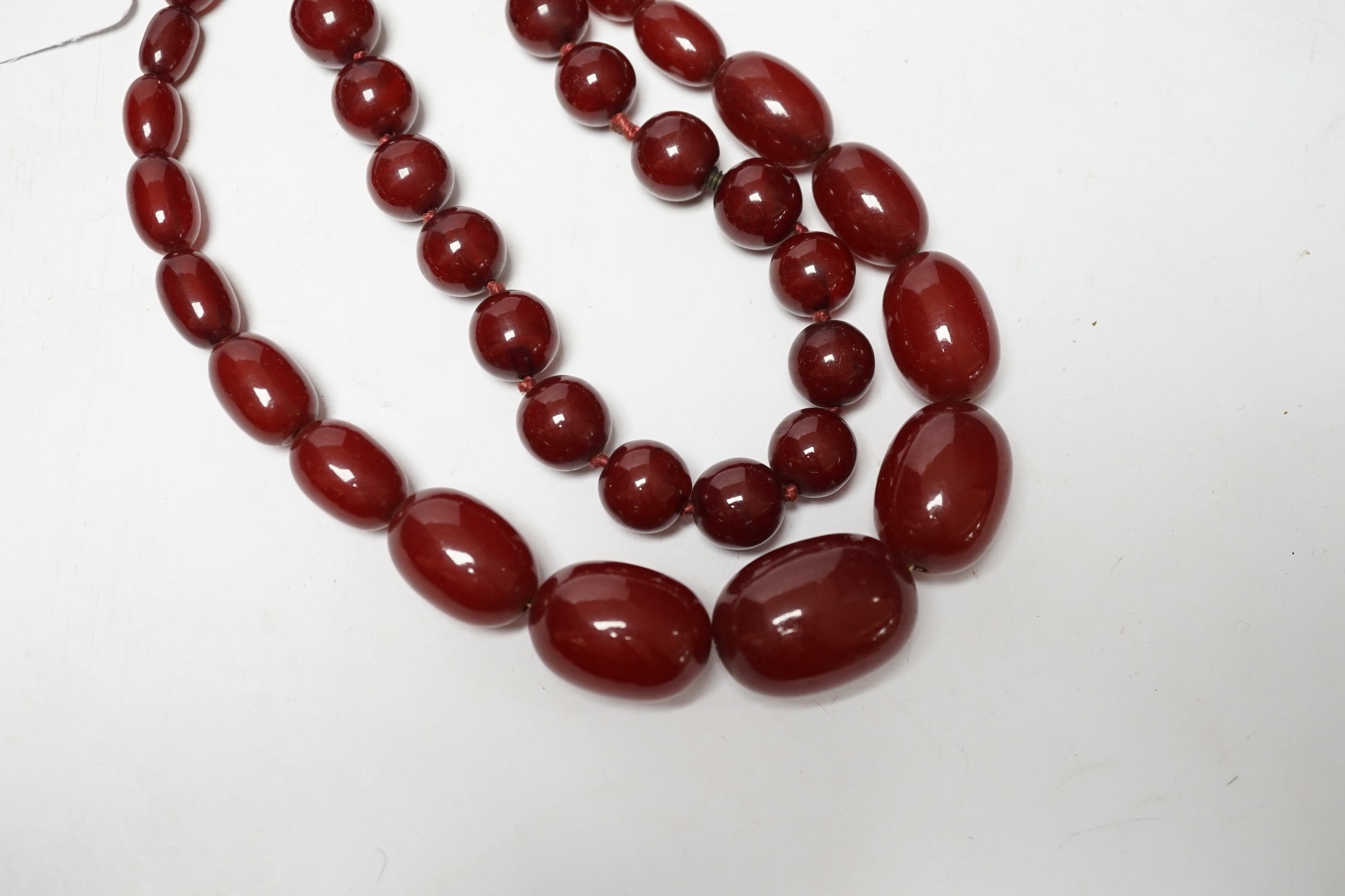 Two single strand simulated cherry amber necklaces, longest 42cm, gross weight 127 grams. Condition - fair